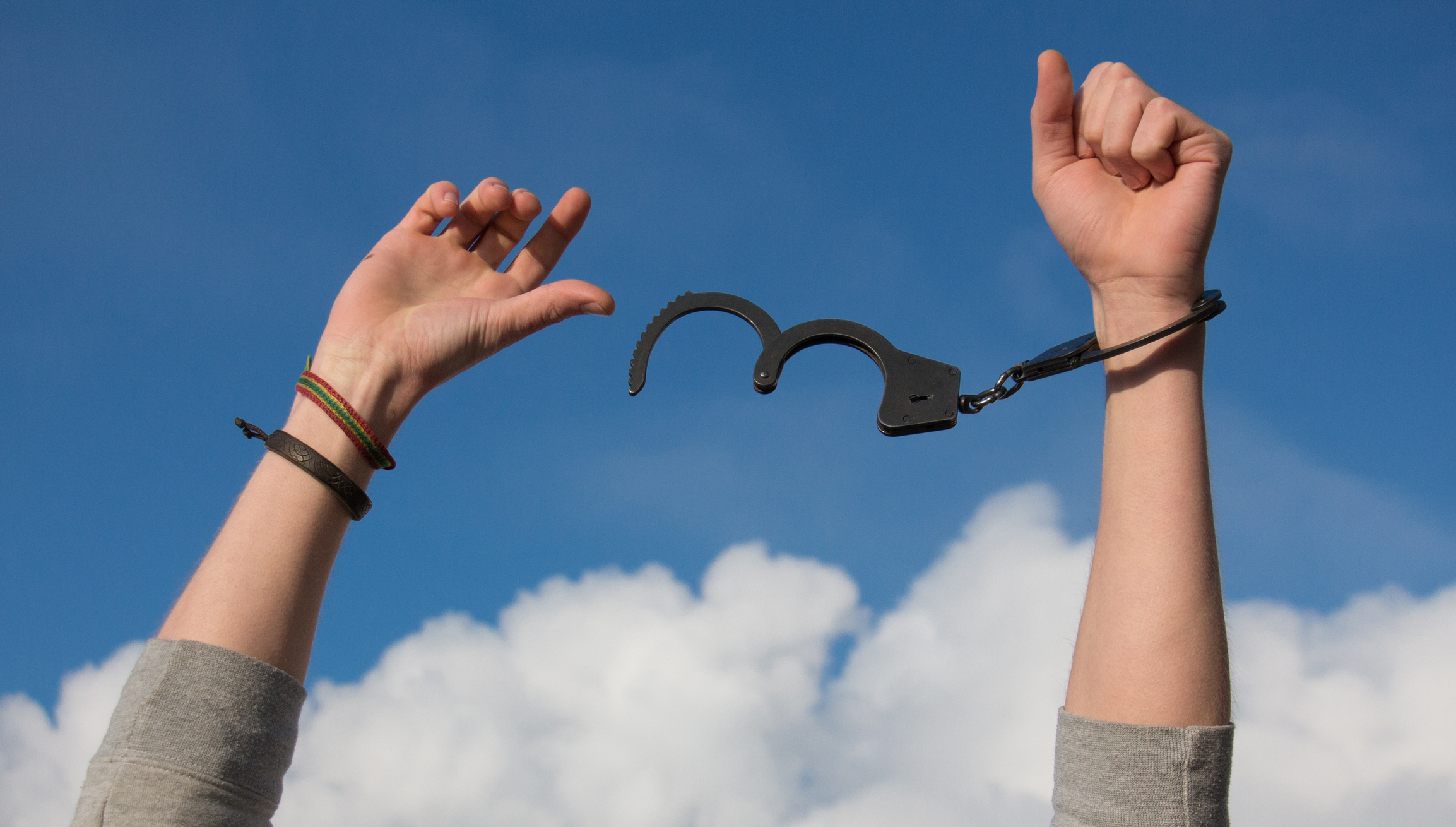 Hands in Handcuffs on Sky Background
